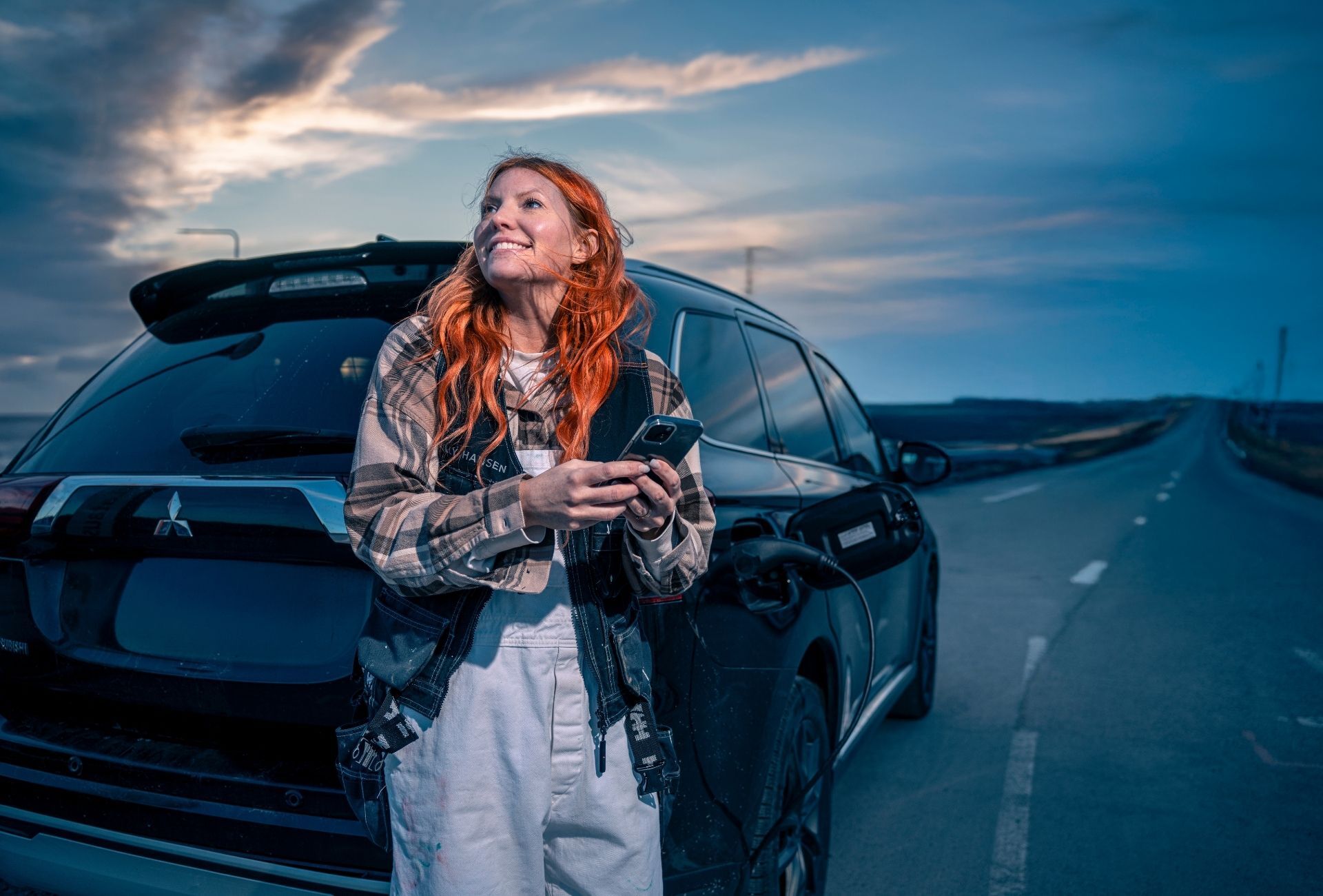 Rakennusalan yrittäjä hymyilee auton vieressä puhelin kädessä